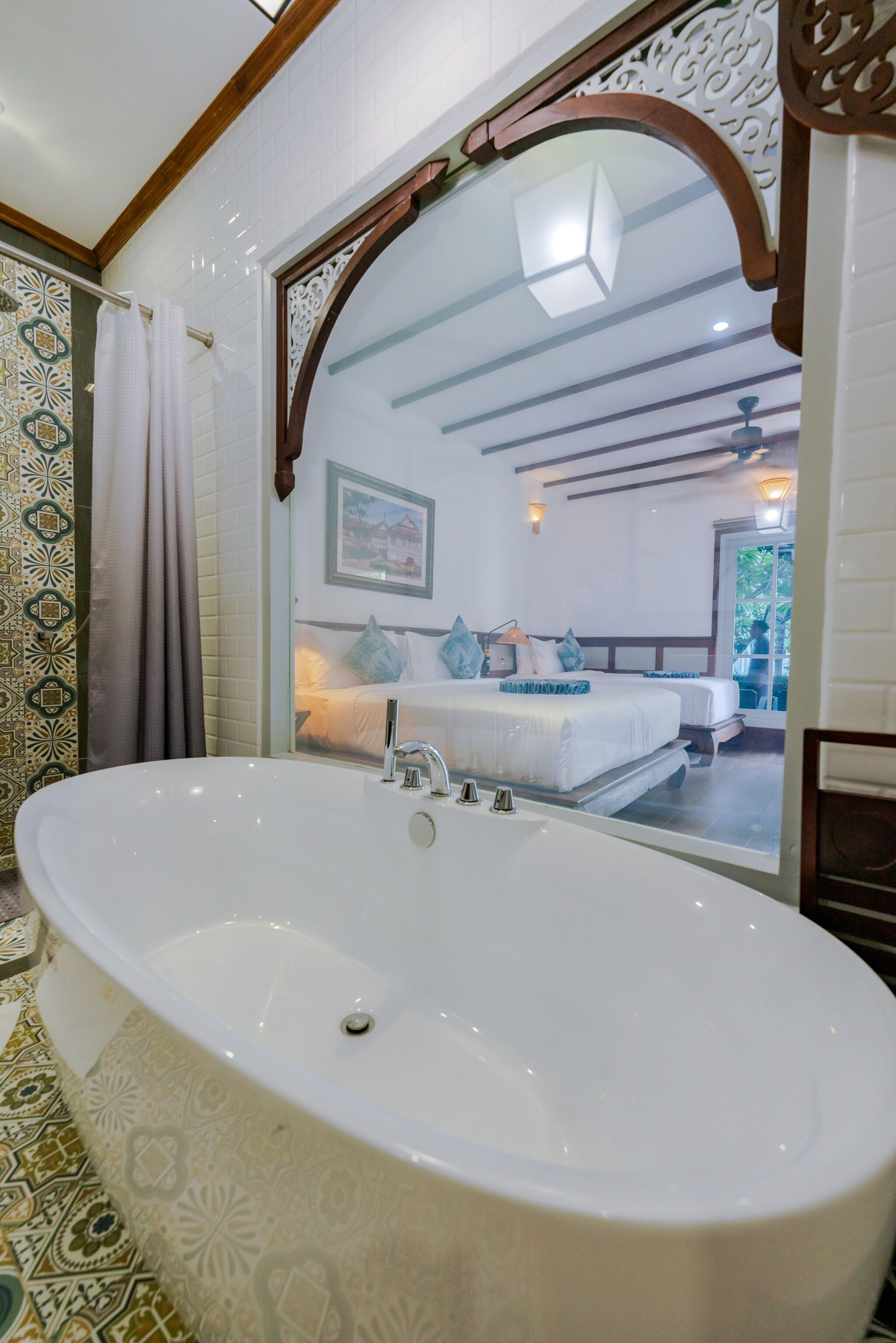 A bathroom with a large freestanding bathtub, a mirror with an ornate frame, and a patterned floor.