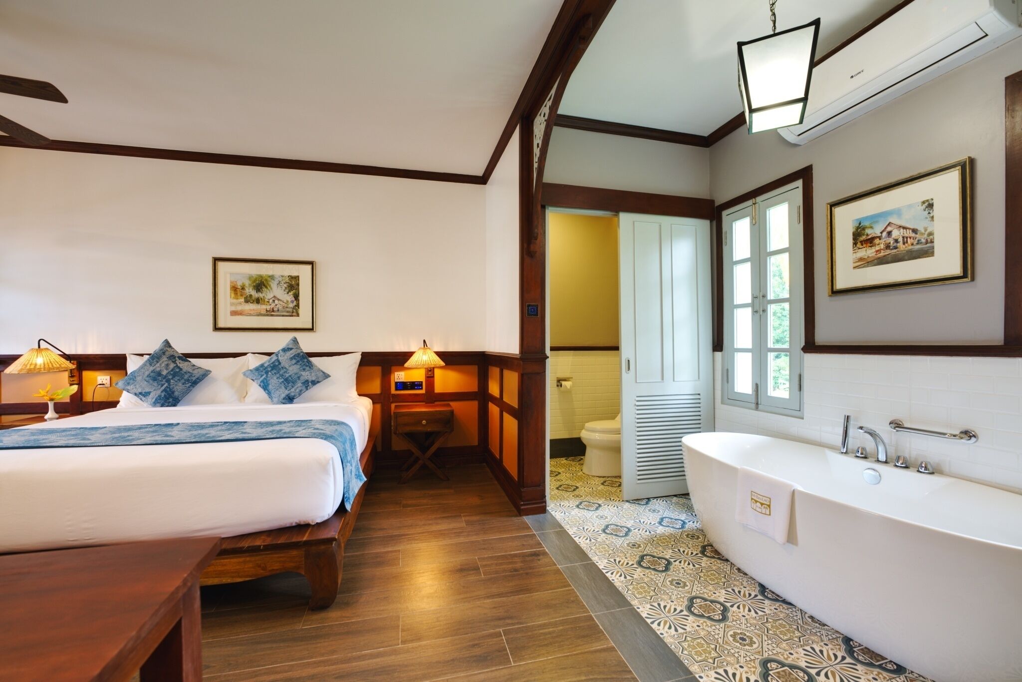 A hotel room with a bed, bedside table, lamp, and a large bathtub.
