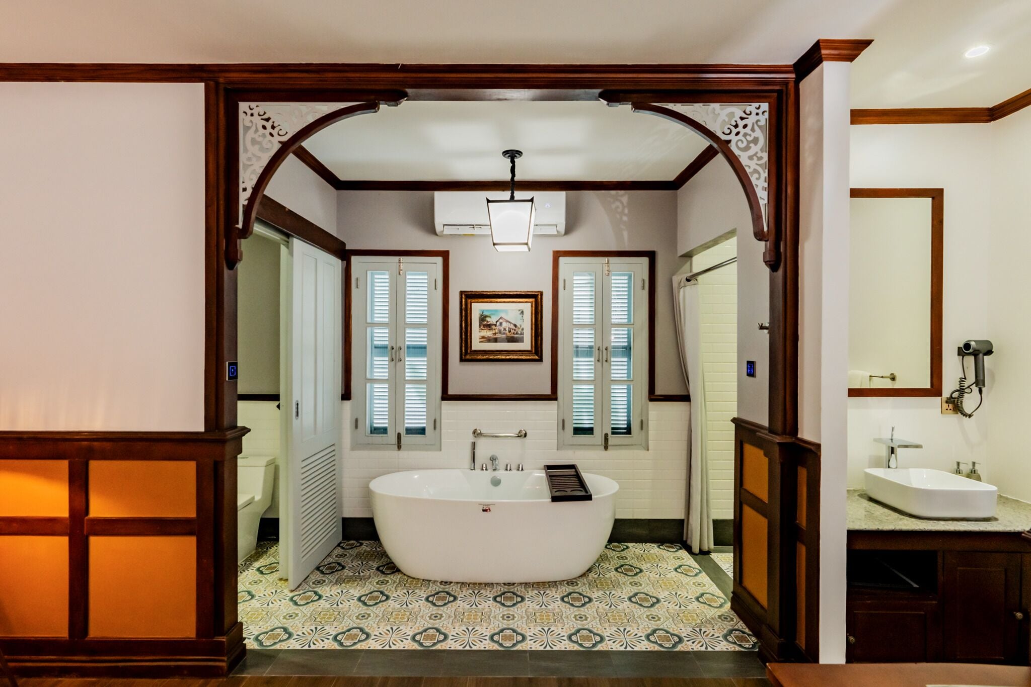 A bathroom with a freestanding bathtub, a sink, and a framed picture on the wall.