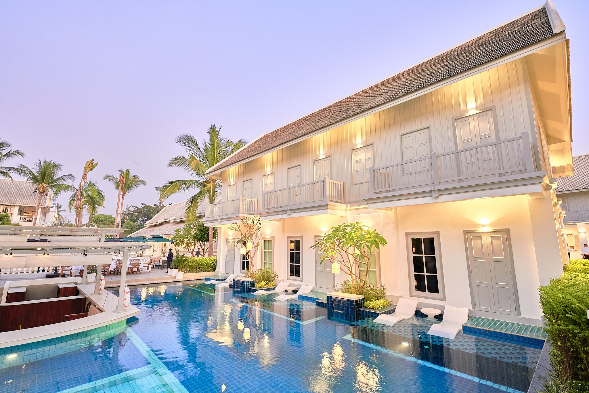 A hotel with a swimming pool, outdoor seating, and a boat dock.