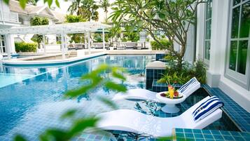 Una piscina con sillas de descanso y una zona de estar cubierta.