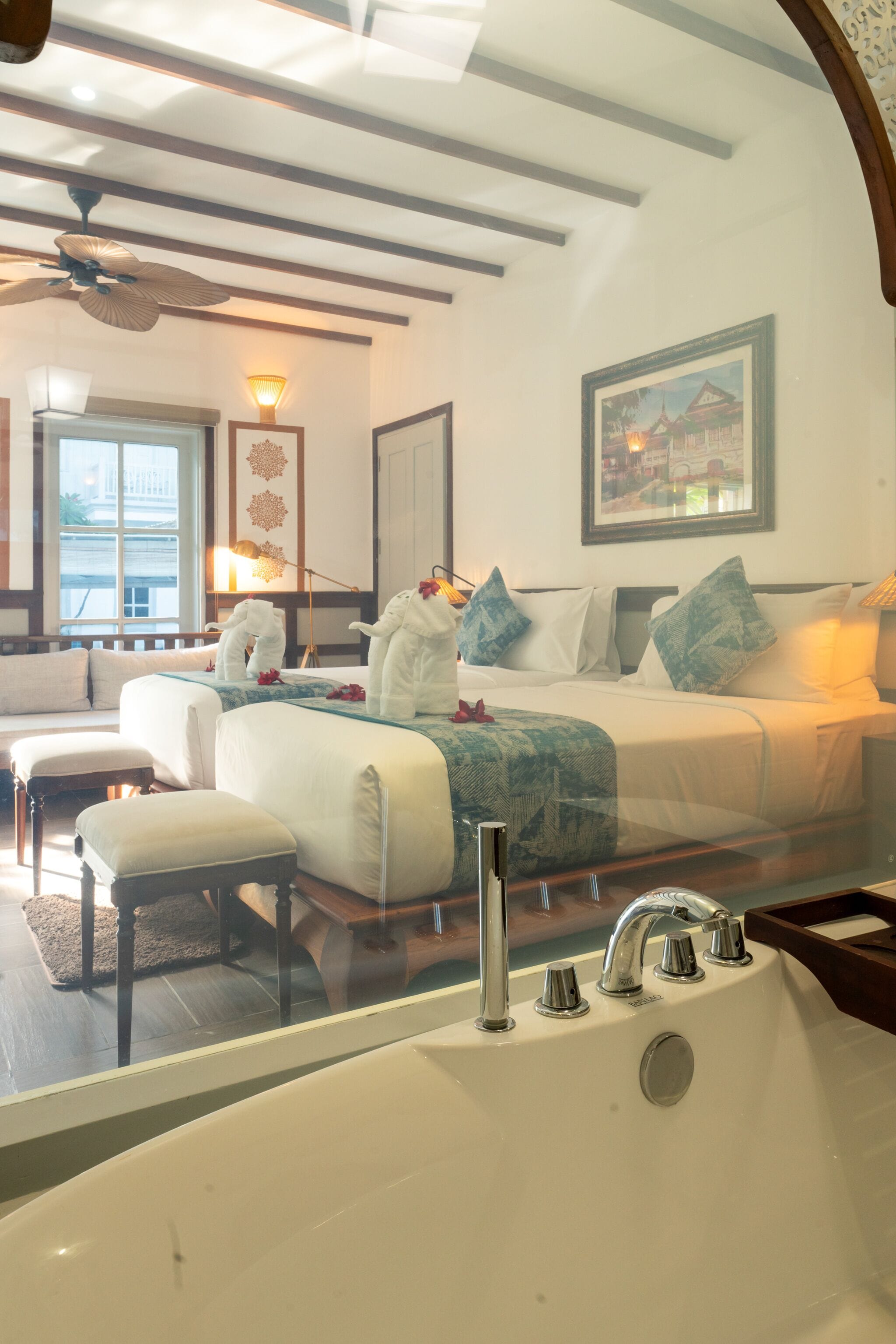 Une chambre d’hôtel avec un grand lit, un coin salon, une baignoire et un ventilateur de plafond.