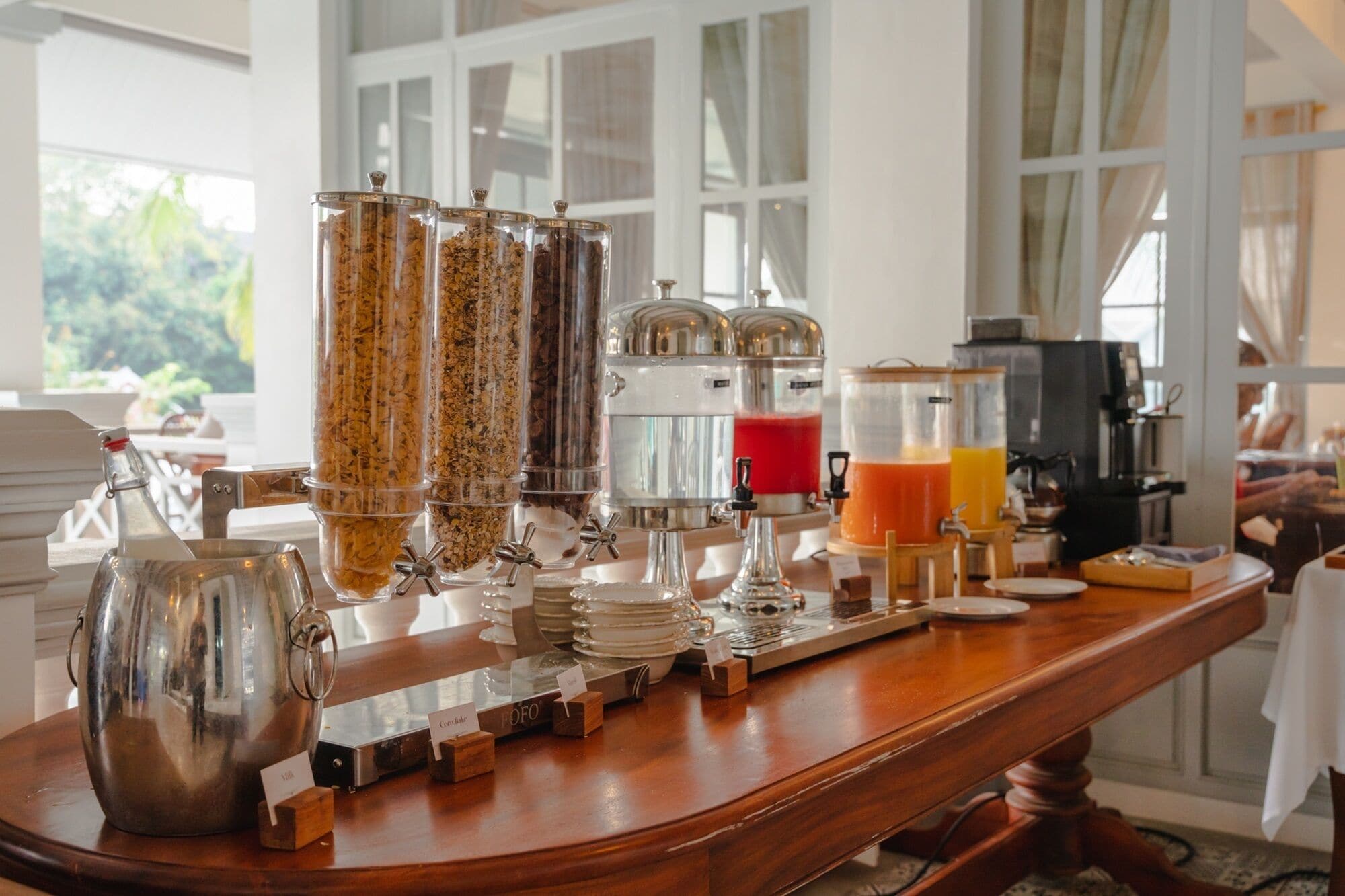 A breakfast bar with various food and drink dispensers, including cereal, coffee, and juice.