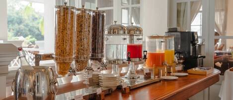 A breakfast bar with various food and drink dispensers, including cereal, coffee, and juice.