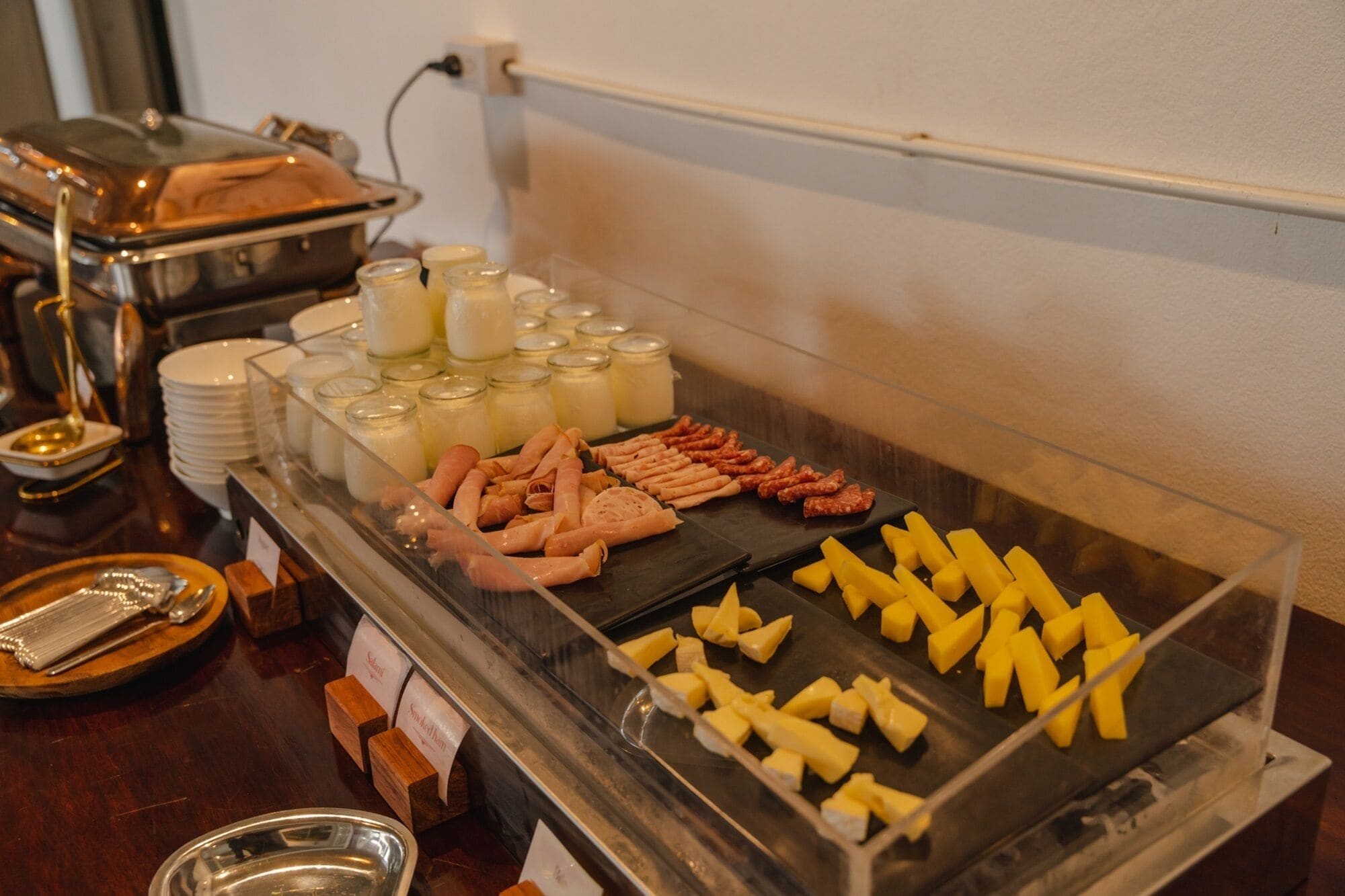 A buffet with various food items including meats, cheeses, and condiments.