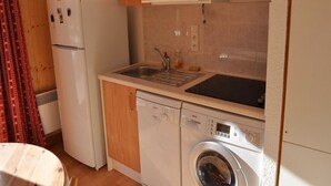 Une cuisine compacte équipée d’un réfrigérateur, d’un four à micro-ondes, d’un évier et d’un lave-linge.