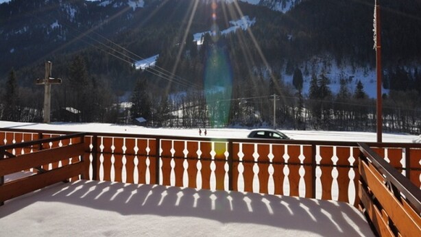 Un balcon offrant une vue sur des montagnes enneigées et un ciel dégagé.