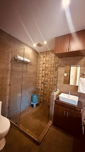 Casa de banho com cabine de duche em vidro, lavatório e sanita.