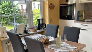 A modern dining area with a table set for two, a coffee machine, and a view of the outdoors.