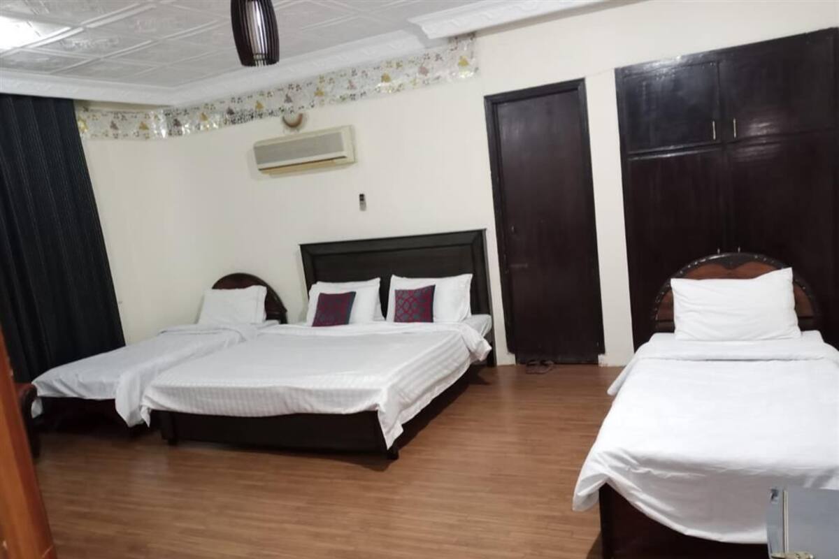 Une chambre d’hôtel avec deux lits, un plancher en bois, un ventilateur de plafond, un appareil de climatisation et une armoire.