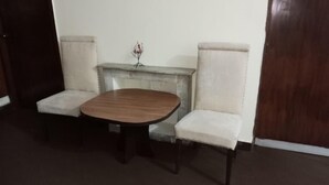 A small, private dining area with a wooden table and two upholstered chairs. - Premier Lodge (Islamabad)