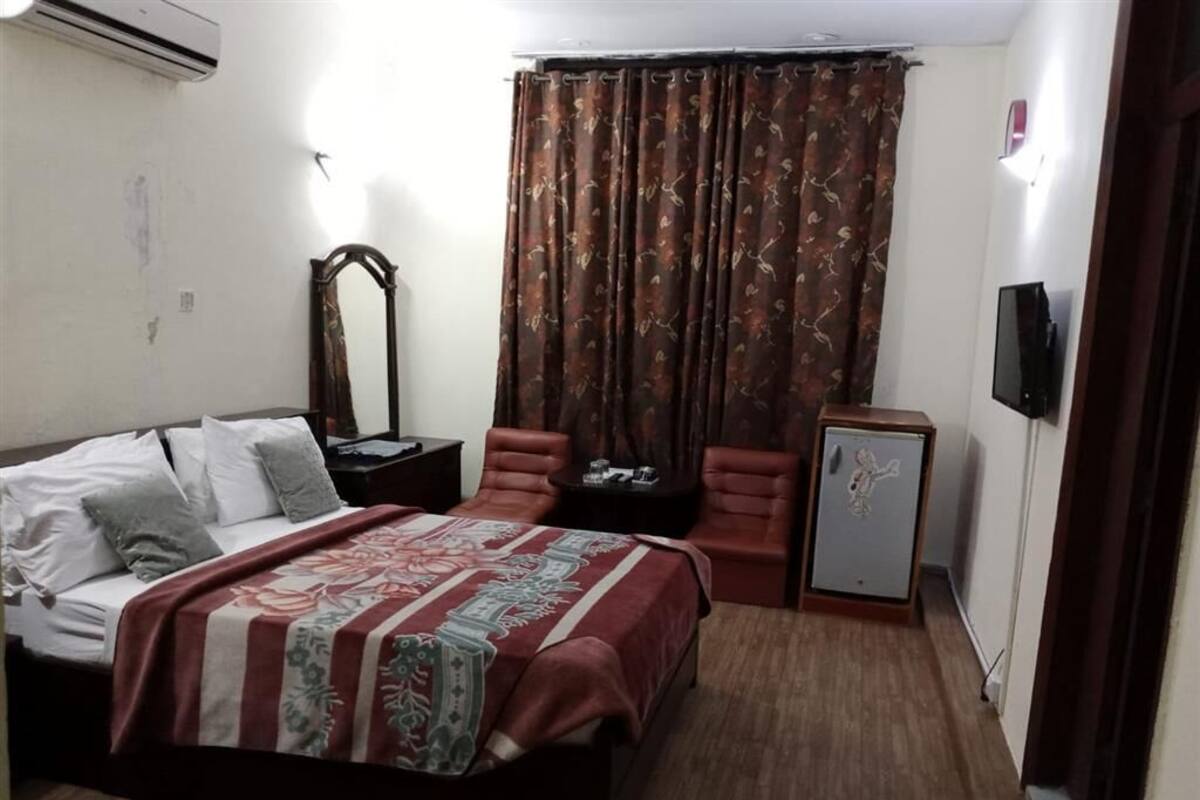 Une chambre à coucher comprenant un lit, un bureau, une chaise, un miroir et un téléviseur.