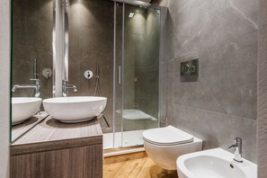 A modern bathroom with two large white sinks, a glass-enclosed shower, a toilet, and a bidet. - Ferrini Home - Riso 80 (Catania)