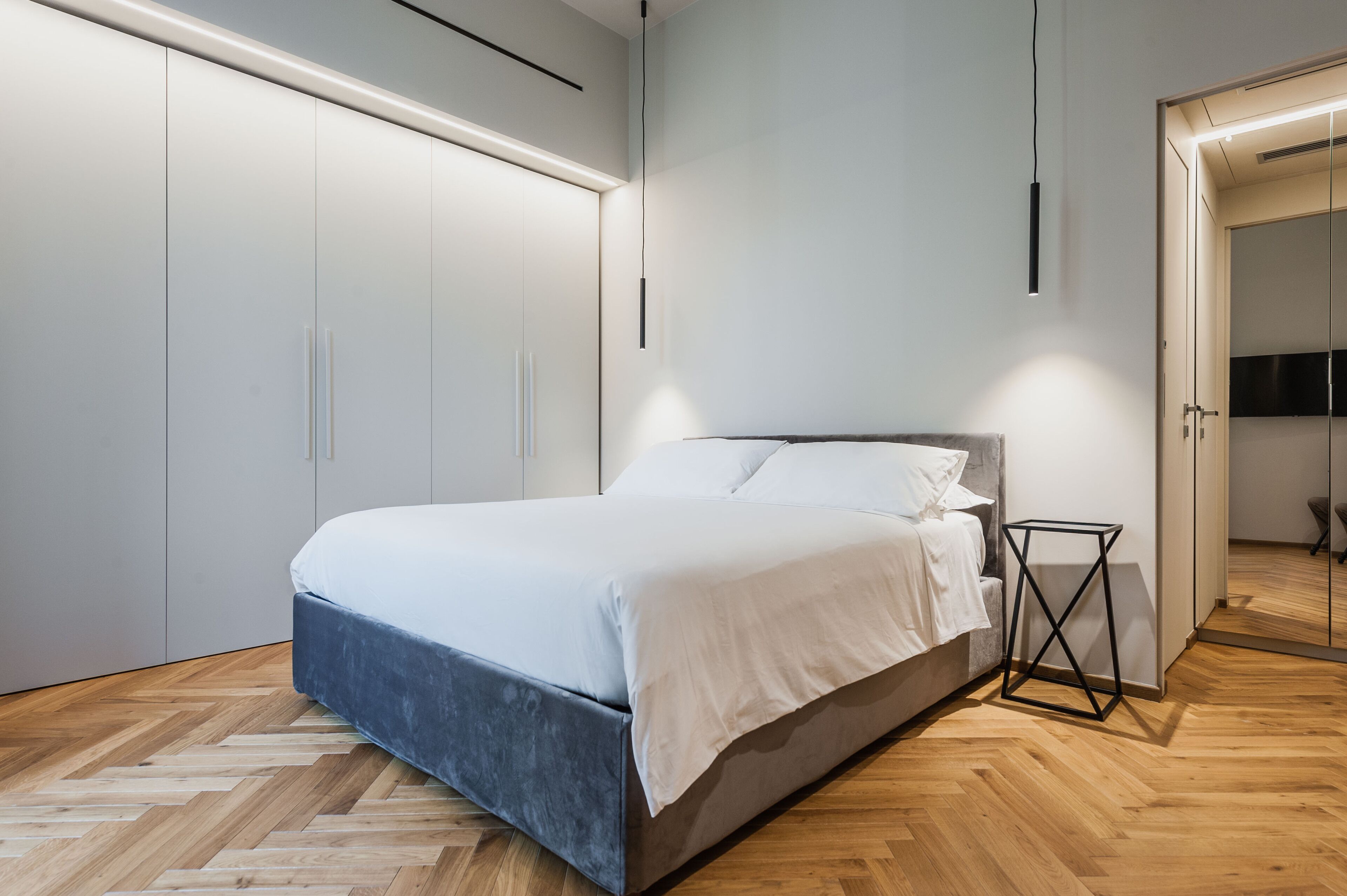 Une chambre moderne avec un grand lit, une armoire intégrée et une table de chevet.