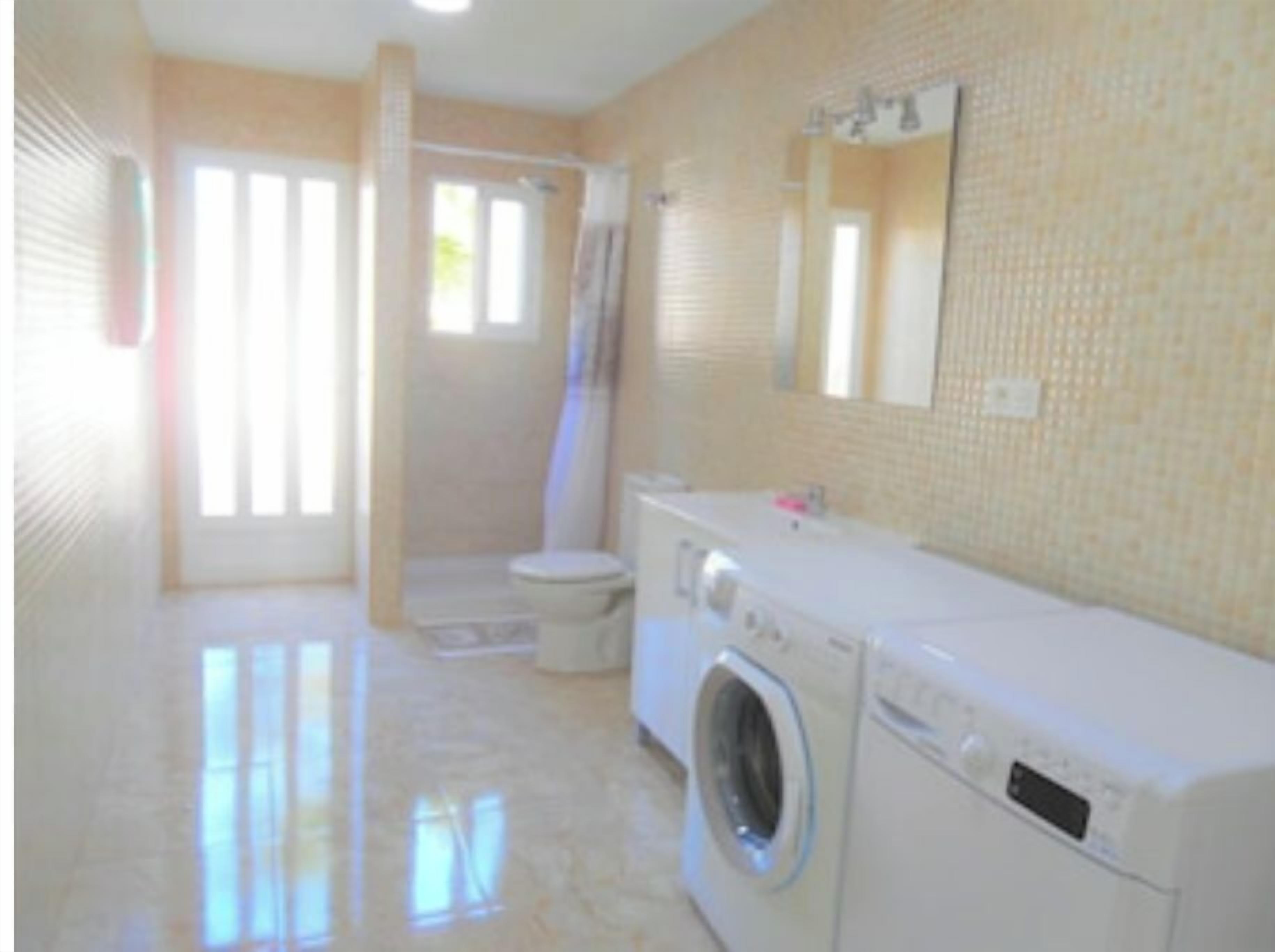 Un baño con inodoro, lavadora y zona de ducha.