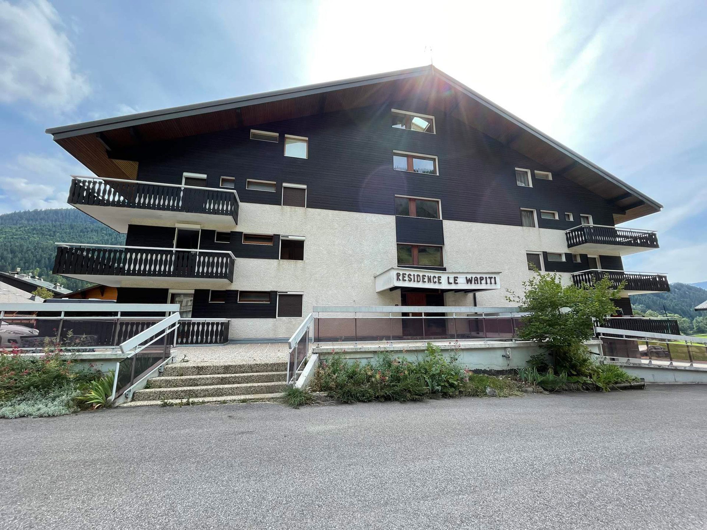 Ein mehrstöckiges Gebäude mit Balkonen und einem Schild, auf dem "RESIDENCE LE WAPITI" steht.