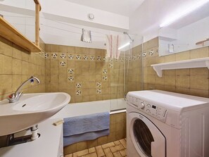 Ein Badezimmer mit Waschbecken, Dusche und Waschmaschine.