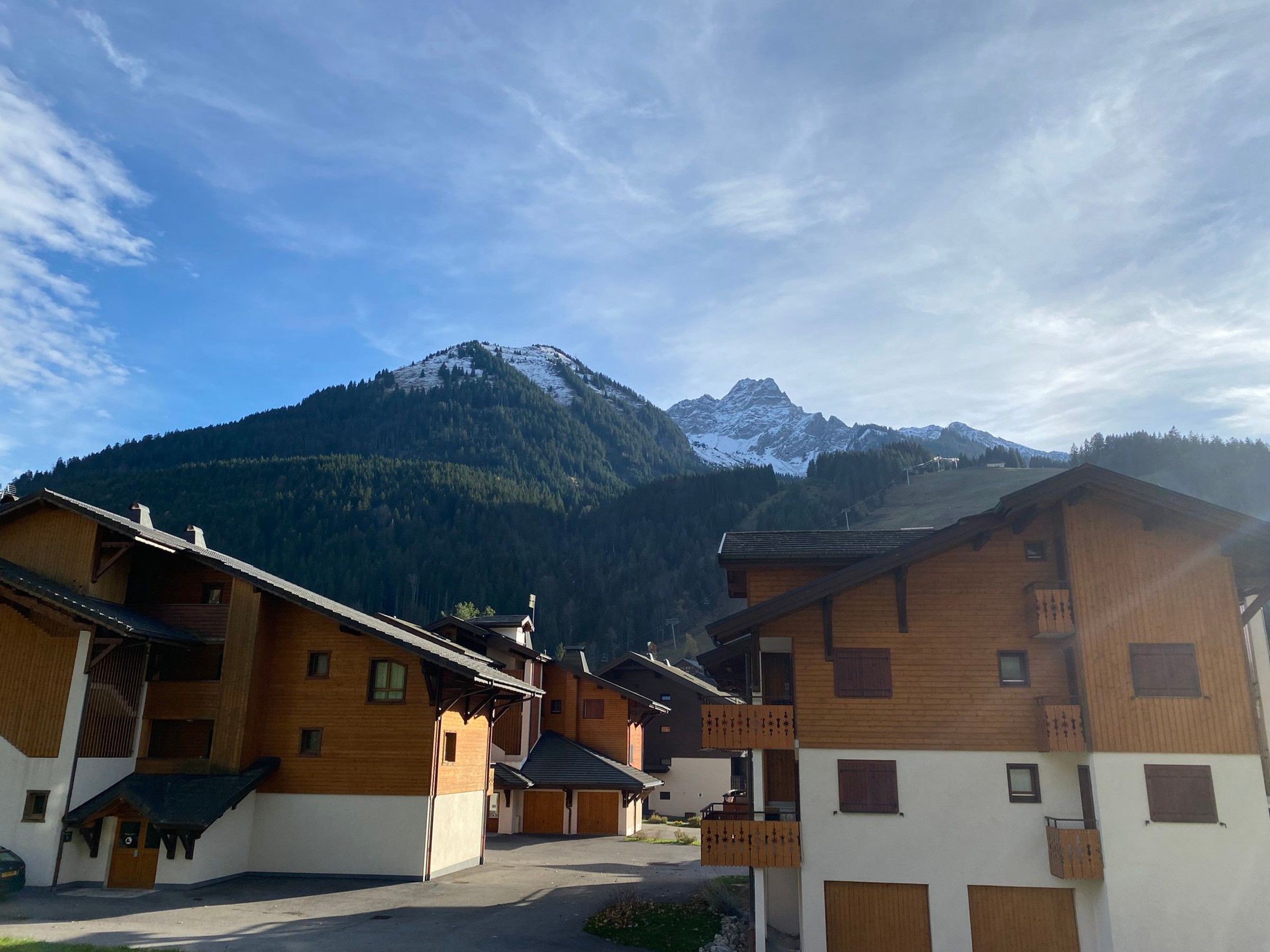 A mountain village with wooden buildings and a snow-capped peak in the background.