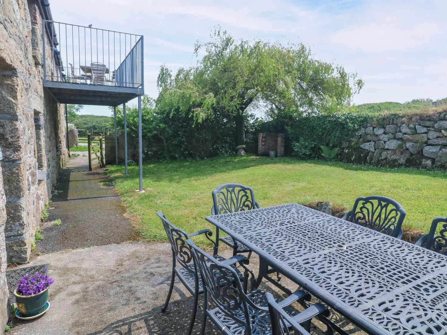 A patio with a table and chairs, a small garden, and a stone wall.