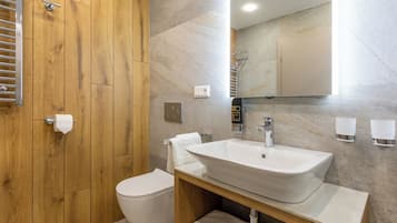 A modern bathroom with a wooden vanity, a white sink, and a toilet.