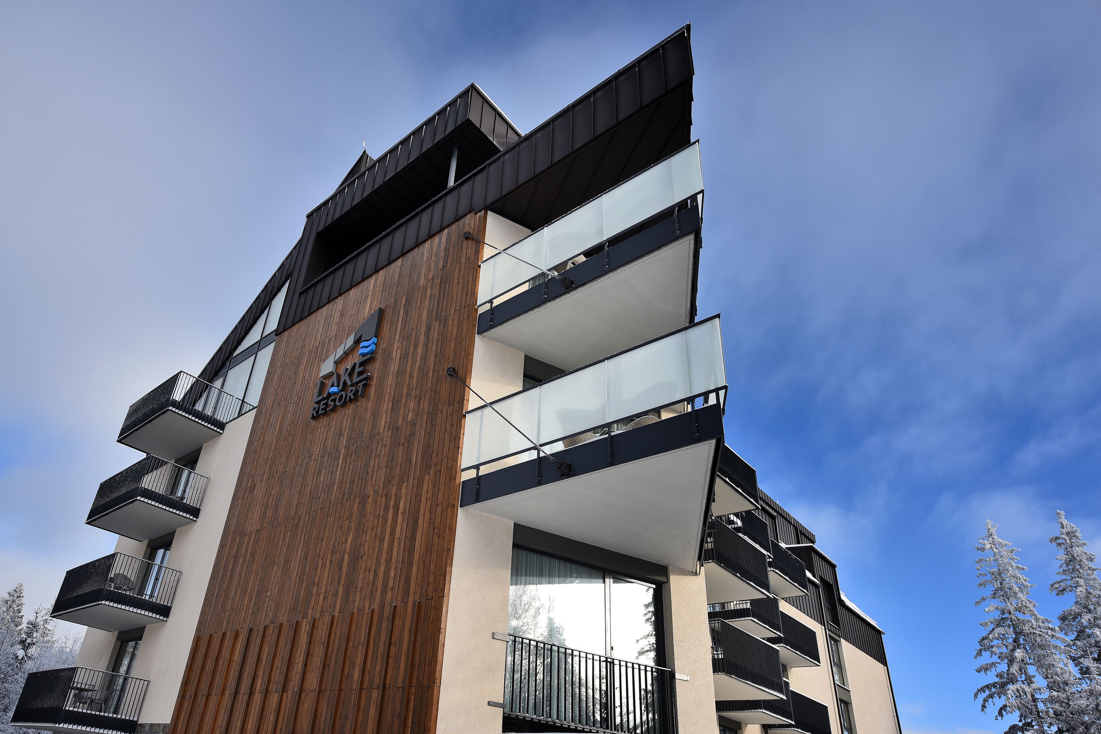 Un hôtel à plusieurs étages, doté d’une architecture moderne, de balcons et d’une façade en bois remarquable.