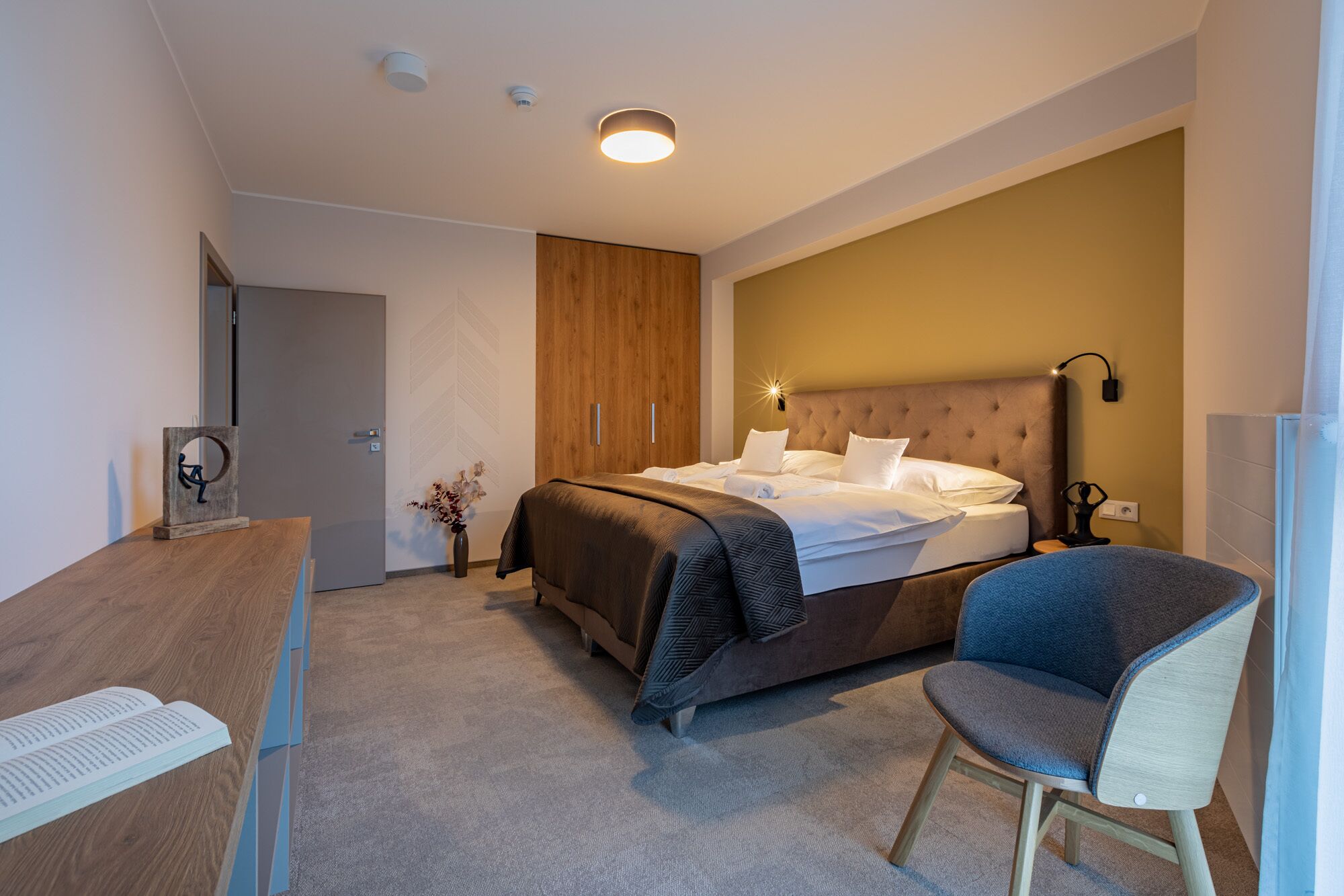 Een moderne hotelkamer met een groot bed, een bureau en een stoel.