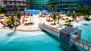 A resort with a pool area, palm trees, and a waterfront view. - voco Monaco Dubai Heart of Europe by IHG (Dubai)