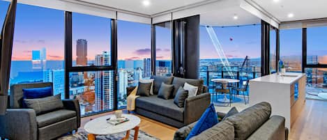 Amplia sala de estar con vistas a la ciudad, un balcón con comedor y una cocina moderna.