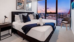 Un dormitorio moderno con una cama grande, una mesita de noche, una silla y un televisor.