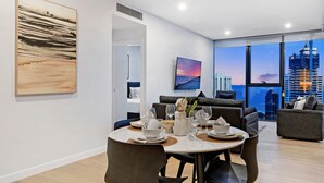 Un comedor moderno con una mesa dispuesta para cuatro personas, un sofá y un ventanal con vistas a la ciudad.