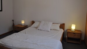A single bed with white bedding, two bedside tables with lamps, and a wooden headboard.