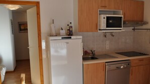 A compact kitchen with a refrigerator, microwave, sink, and dishwasher.