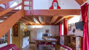 A cozy cabin interior with a dining area, kitchen, and a loft bedroom with a staircase. - Cozy Chalet with 3 Bedrooms, Terrace, Parking, Near Cauterets Center (Cauterets)