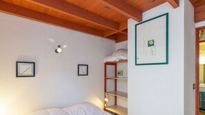 A bedroom with a bunk bed, a wooden ceiling, and a white wall with framed pictures. - Cozy Chalet with 3 Bedrooms, Terrace, Parking, Near Cauterets Center (Cauterets)