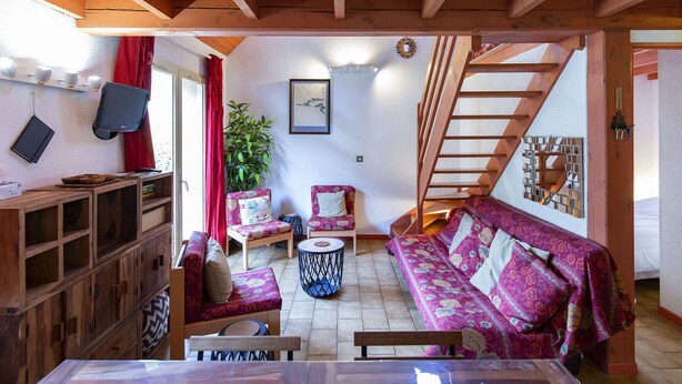 A cozy room with wooden beams, a sofa set, a dining table, and a staircase. - Cozy Chalet with 3 Bedrooms, Terrace, Parking, Near Cauterets Center (Cauterets)