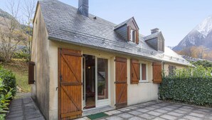 A chalet with a stone facade, wooden shutters, and a tiled patio. - Cozy Chalet with 3 Bedrooms, Terrace, Parking, Near Cauterets Center (Cauterets)