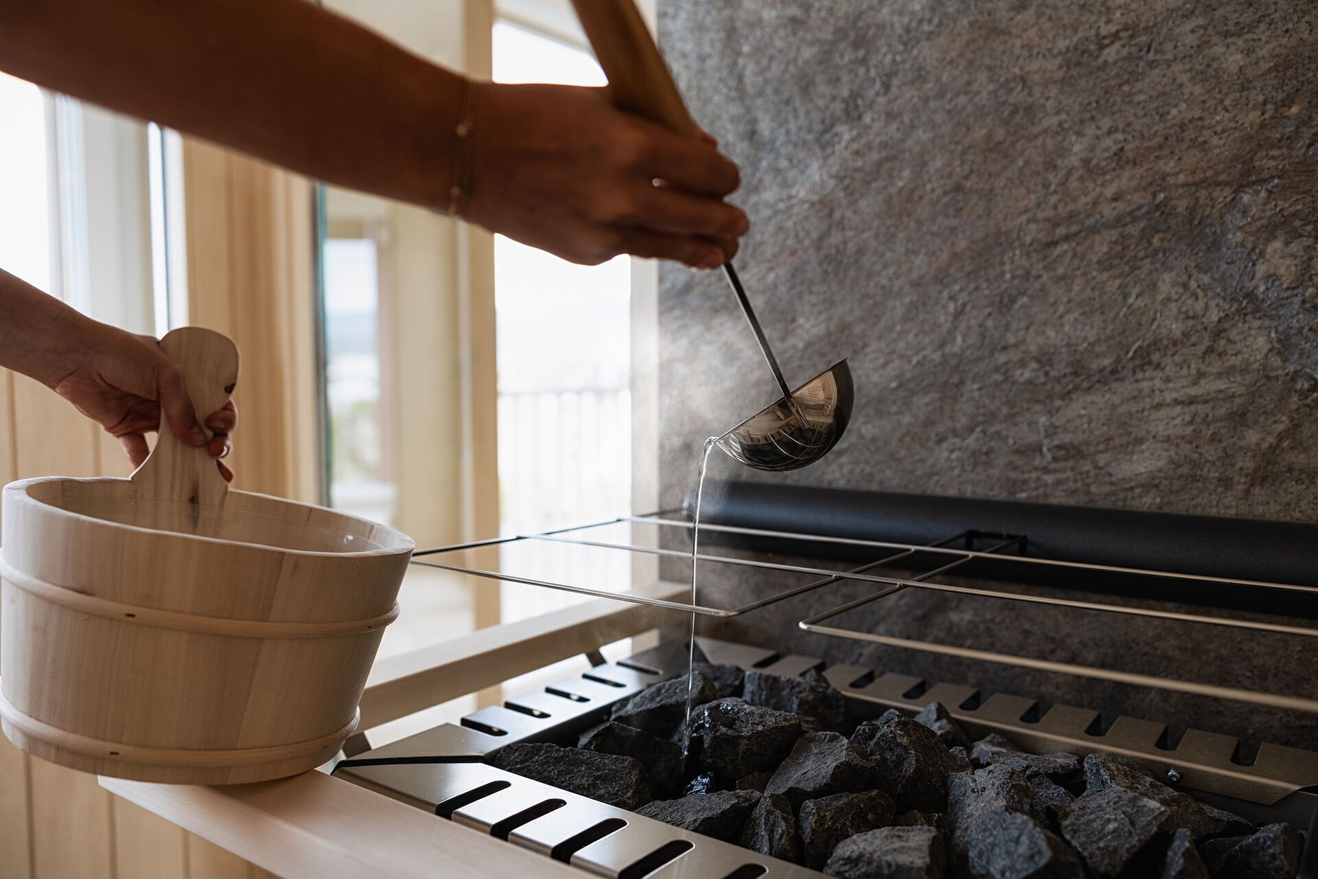 En person använder en slev för att ösa upp kol från en grill.