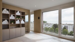 A spacious balcony with a view of the city and sea, a built-in shelf with towels and plants, and a modern interior design. - bsmart hotel Arbon (Arbon)