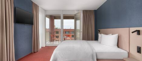 A hotel room with a large bed, a flat-screen TV mounted on the wall, and a balcony with a chair.