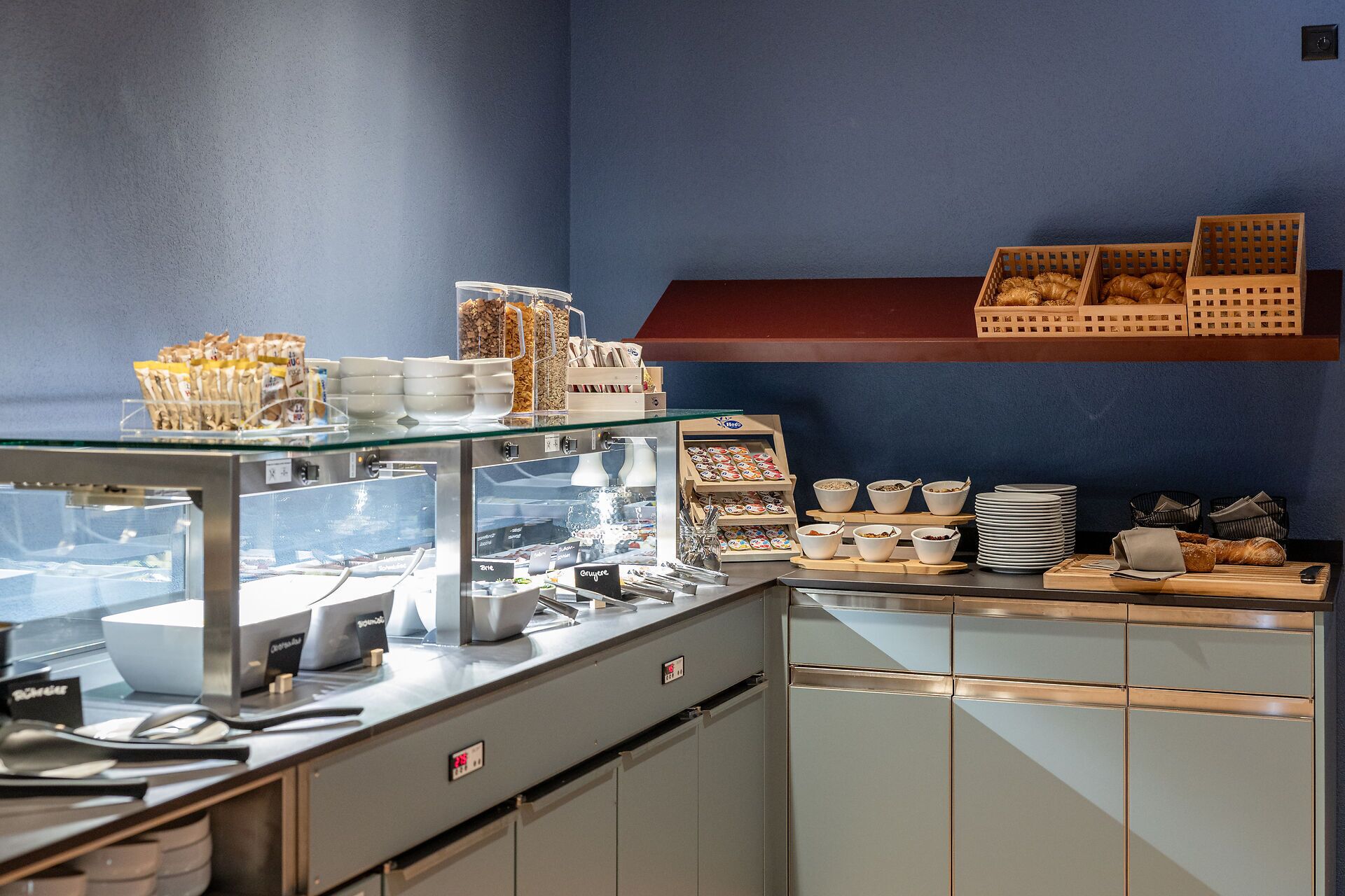 A breakfast buffet area with various food items and utensils.