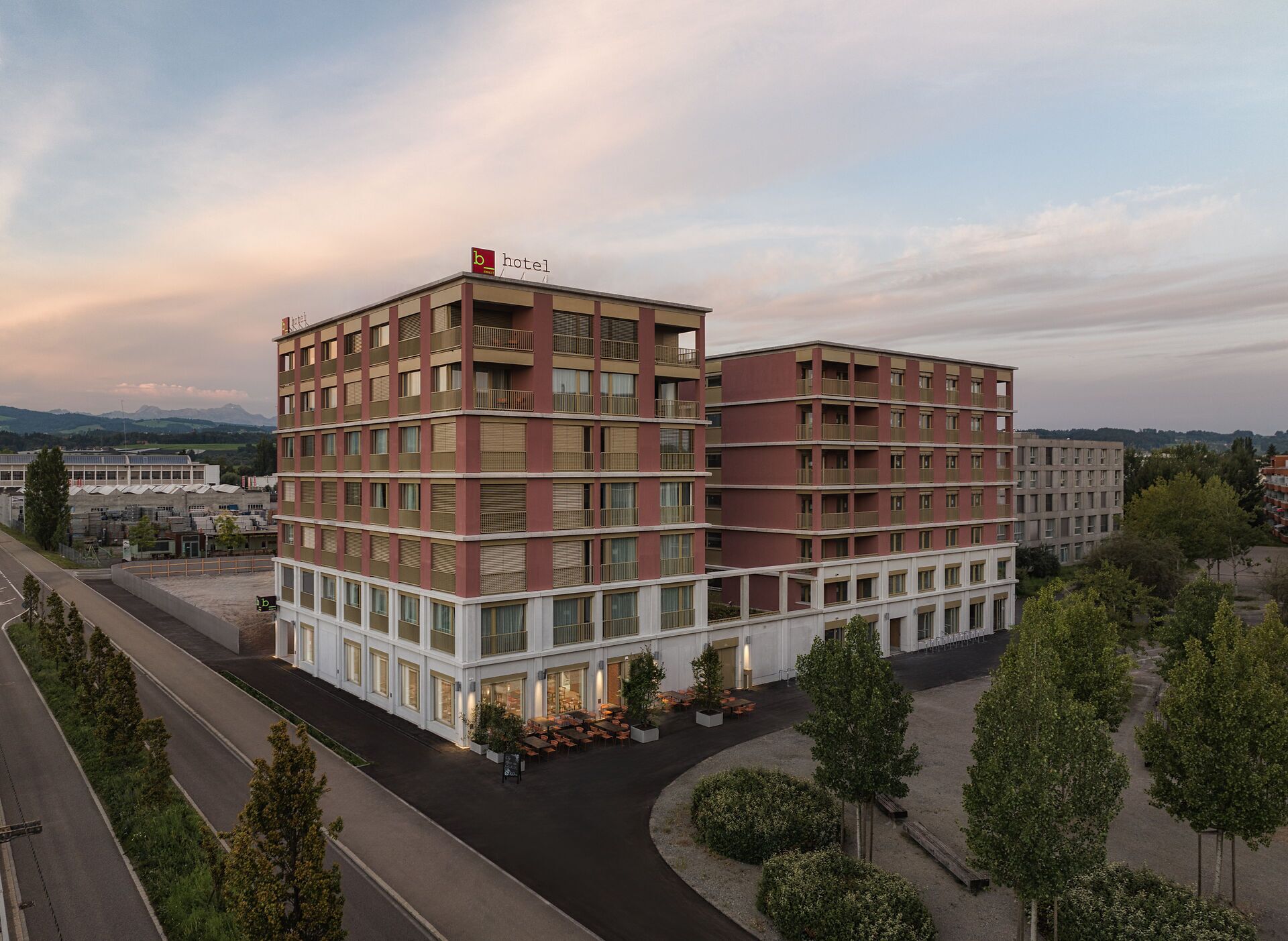 A multi-story hotel with a modern design, featuring balconies on the upper floors and a ground-level entrance.