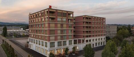 A multi-story hotel with a modern design, featuring balconies on the upper floors and a ground-level entrance.