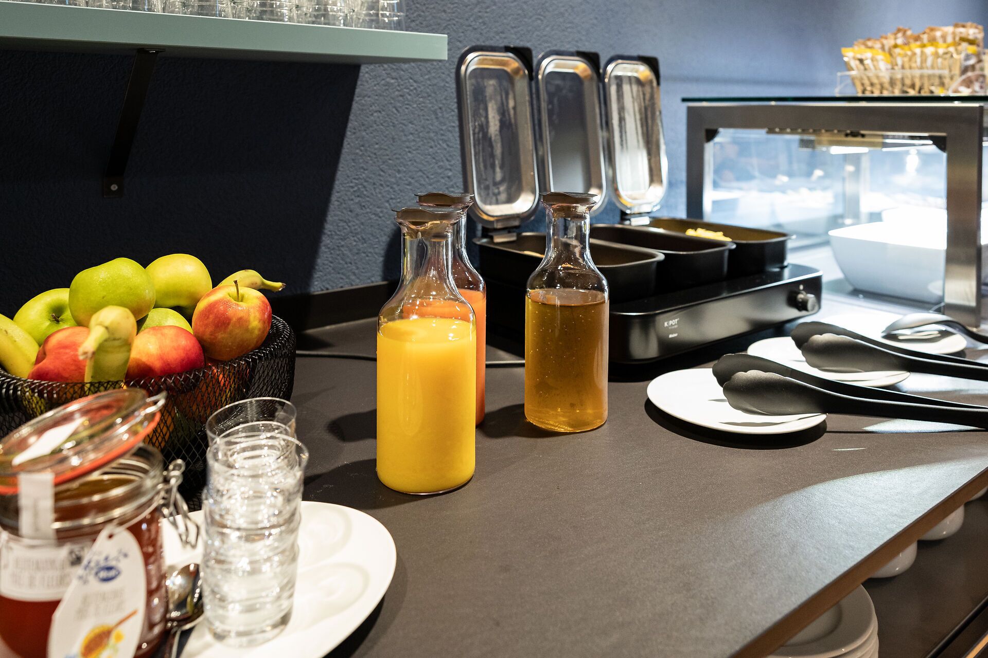 Een ontbijt met fruit, vruchtensappen en een wafelijzer.