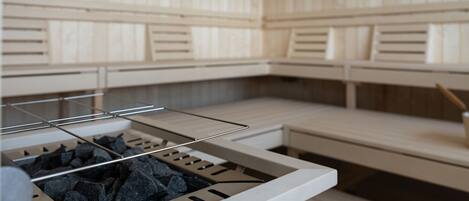 A sauna room with wooden benches and a metal rack holding towels.