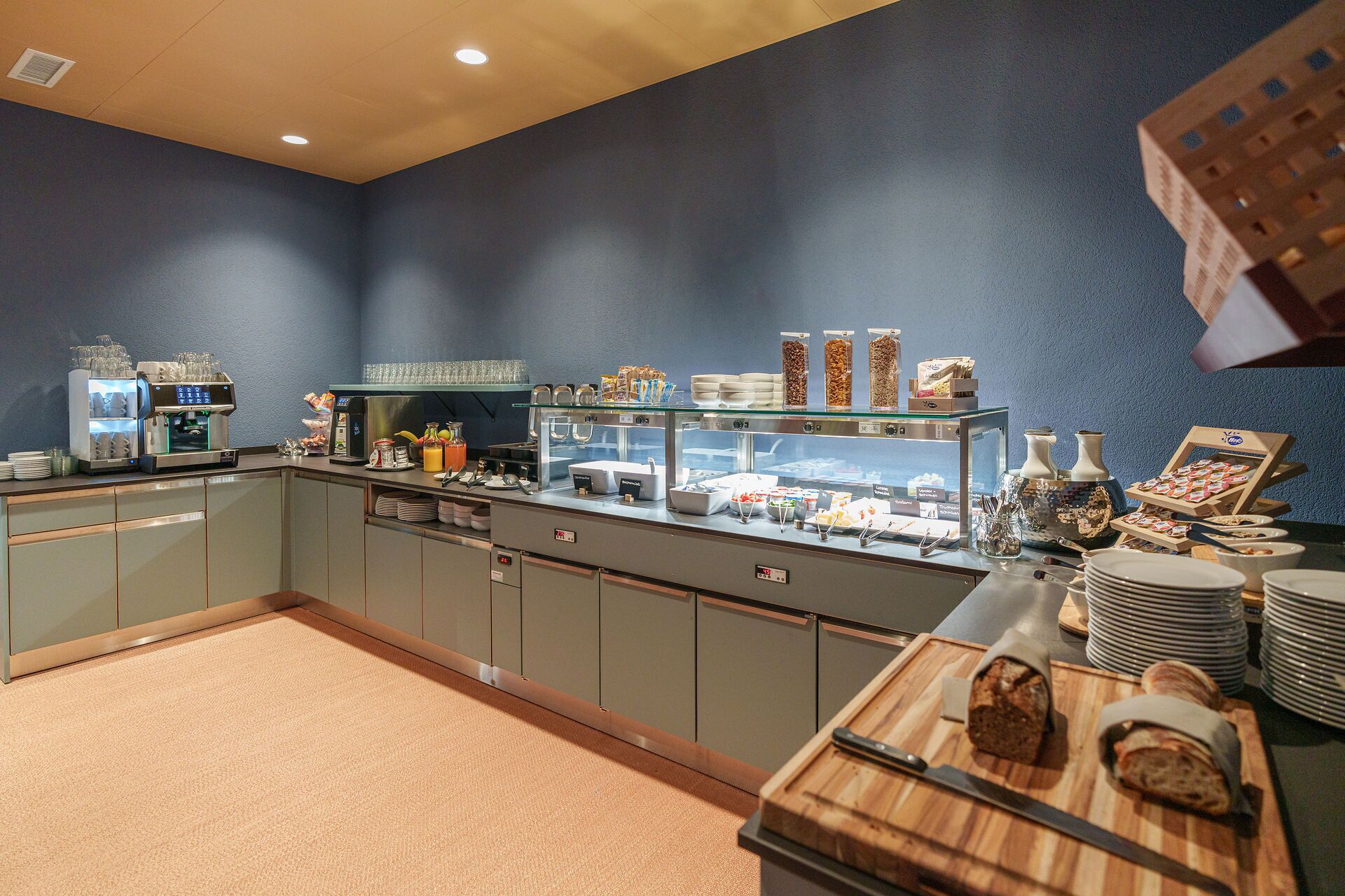 A breakfast buffet with a coffee machine, cereal, and pastries.