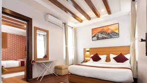 Et moderne hotelværelse med en træseng, et spejl, et lille bord og udsigt til et bjerg.