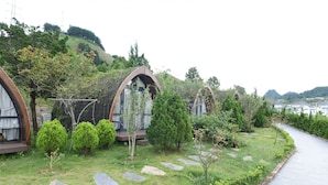A series of dome-shaped cabins with a grassy garden and a stone pathway. - Family 64 Home (Van Ho)