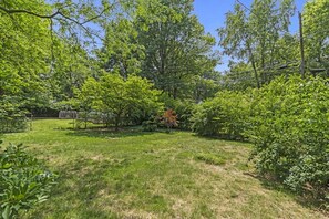 A grassy backyard with trees and a garden structure. - The Sunnyside- Waldo Ranch + Fenced Yard + Parking (Kansas City)