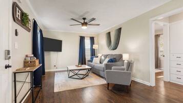 A living room with a sofa, a coffee table, a TV, and a ceiling fan.