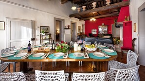 Un'area pranzo con un tavolo di legno apparecchiato per sei persone, circondato da sedie bianche.